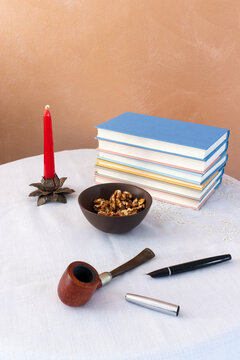 Elegant still life with stacked books, pipe and walnuts on refined white table setting
