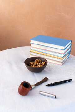 Elegant still life with stacked books, pipe and walnuts on refined white table setting