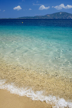 Crystal clear turquoise sea lapping sandy beach.