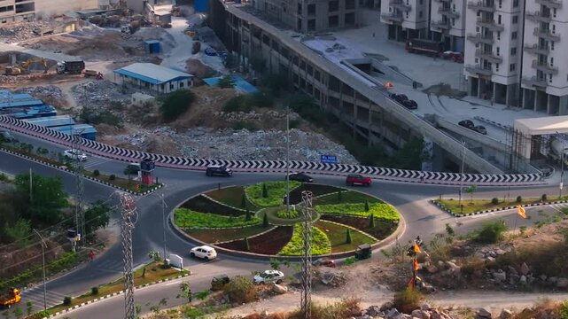Vehicle using roundabout near lanco hills to ORR service road and under construction building at Makthakousarali, Khajaguda, hyderabad, telangana, india. day time, arc shot, drone shot, 4k.