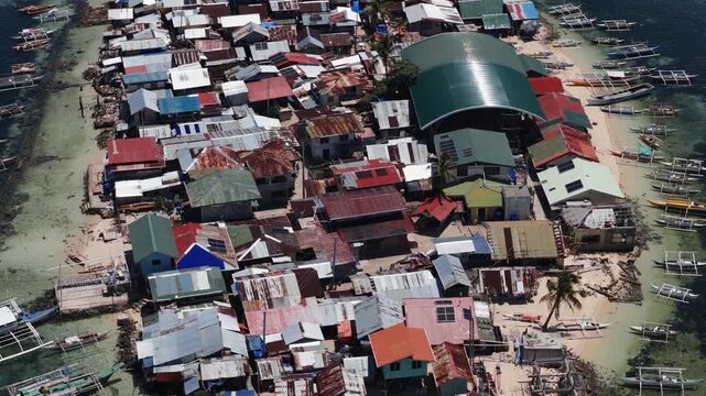 Low altitude drone orbit over crowded Bilangbilangan island homes and waterfront fishing boats, aerial
