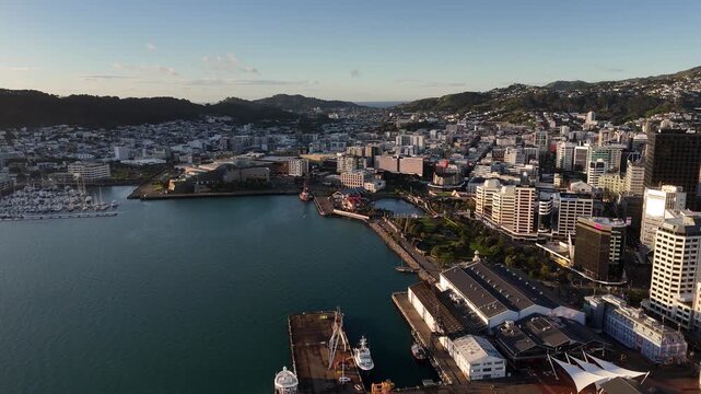 This drone footage from 1.png captures a stunning sunrise over Wellington City, New Zealand. The 4K aerial view reveals the calm harbor, modern skyline, and scenic coastal hills in the morning glow