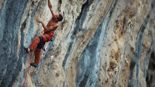 extremely focused rock man climber climb tough route on vertical rock cliff. human strength and power, muscular strong sportsman training outdoors