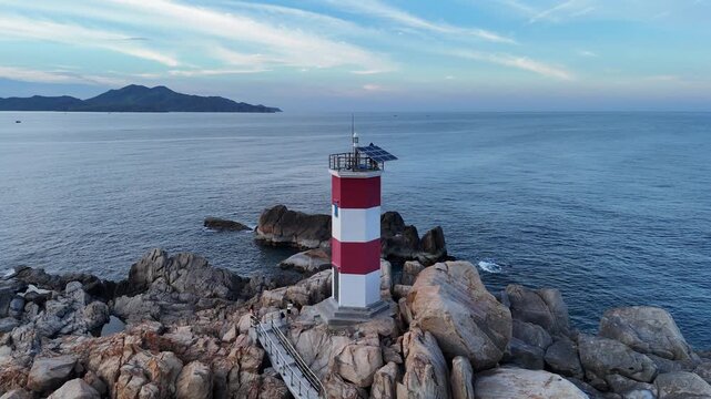 GANH DA DIA, PHU YEN, VIETNAM - JUNE 26, 2026: Drone footage captured flying from the rocky shoreline over Ganh Den Lighthouse toward the open sea in Dak Lak (formerly Phu Yen) Province, Vietnam. The 