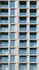 Fototapeta premium Repeating glass balconies on a modern concrete building facade. Minimalist architectural design creates urban symmetry. Ideal for real estate, urban planning, and construction marketing.