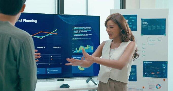 Group of Asian businesspeople work together leads business meeting uses presentation TV with revenue, profit or sale statistics in office. Financial generation z team brainstorm on e-Commerce project.