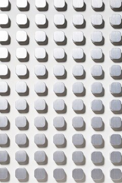 Abstract pattern of silver metal square studs on white background vertical