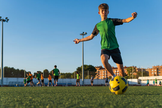 Young boy playing soccer on artificial turf field