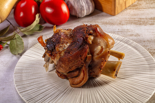 Hearty roasted pork knuckle with fresh vegetables on a rustic plate