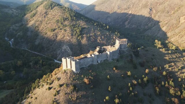 Ascending aerial footage shows the majestic stone ruins of Maglic fortress nestled among the rolling hills of Southwestern Serbia.