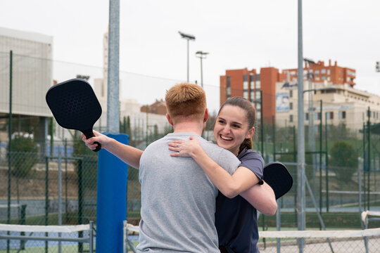 Two pickleball players embracing and celebrating their win on a sports court