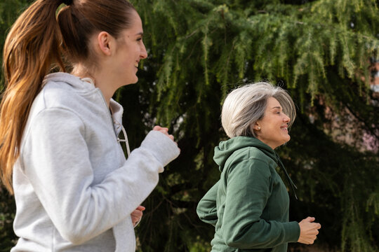 Two women smiling and jogging outdoors, staying active and healthy