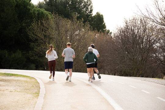 Group of diverse adults jogging outdoors on a park path, staying active and healthy