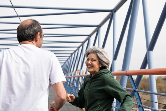 Active senior couple walking and talking on a modern bridge