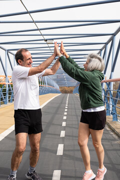 Senior couple high fiving after an outdoor workout, celebrating health and triumph