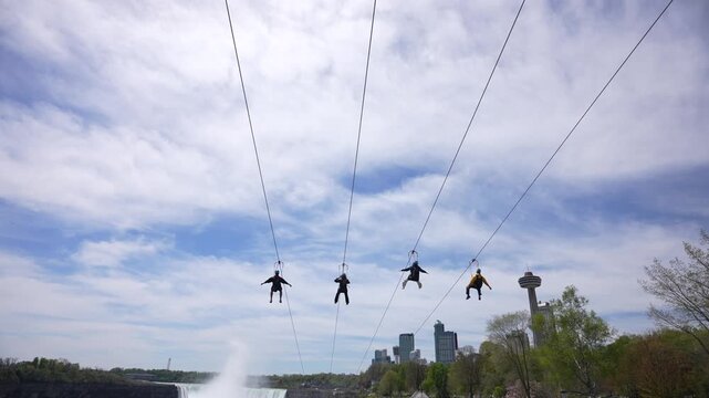 View of people on zip wires with the American Falls and Horseshoe Falls in background from Canada on a sunny day, Niagara Falls, Ontario, Canada, North America