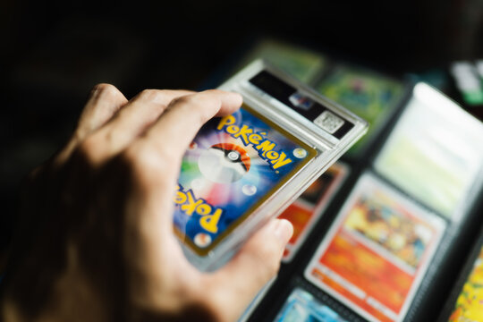 Bangkok, Thailand - July 12, 2026 : Close Up of a Collector Hand Holding a Rare Graded Pokemon Trading Card in Protective Plastic Case.