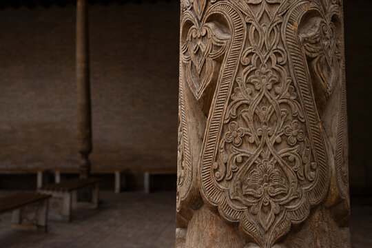 Carved wooden column with intricate floral patterns at Pakhlavan Makhmoud Mausoleum in Khiva. Traditional Central Asian woodcarving detail ideal for heritage, travel, and cultural publications.
