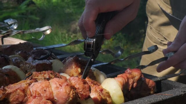 A horizontal close up shot of hands using a multitool knife to cut and check cooking shashlik skewers on a barbecue grill, perfect for outdoor gear branding and culinary marketing.