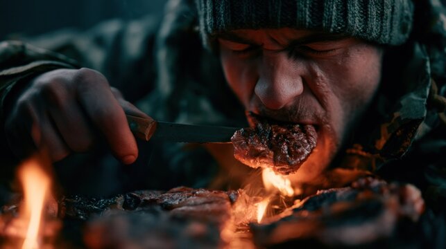 Man eating grilled steak by campfire