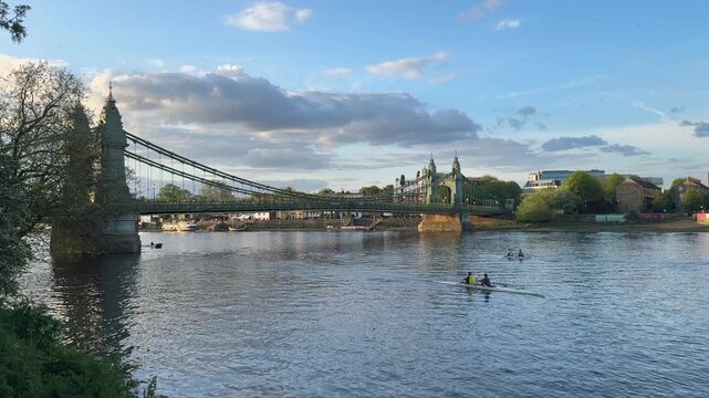 Two rowing teams pass along The River Thames underneath Hammersmith Bridge, London, United Kingdom