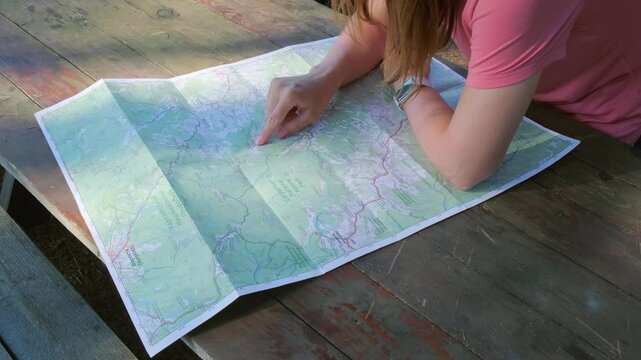 A horizontal tracking shot of people pointing at hiking trails on a paper map of Carpathian National Nature Park, ideal for eco tourism marketing and outdoor travel storytelling.