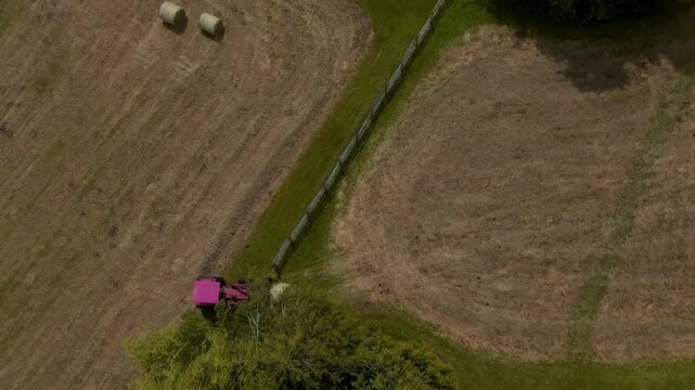 High aerial drone shot of a modern tractor working across a large agricultural field in the British countryside. Expansive farmland and precision farming machinery showcase efficient agricultural oper