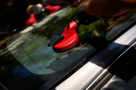 Detailed close-up of a vacuum grip seating auto glass onto automotive sealant during an outdoor windshield replacement process
