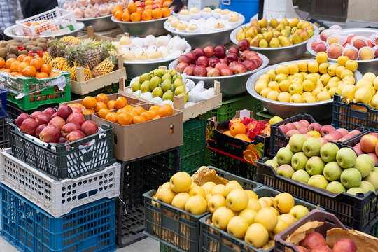 Fresh fruit display at an oriental bazaar with apples, pears, tangerines, and pineapples in crates and metal bowls. Ideal for travel content, food marketing, or healthy eating campaigns.