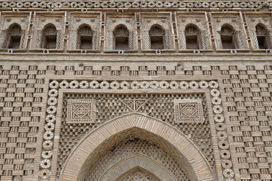 Ornate brickwork facade of the Ismail Samani Mausoleum in Bukhara featuring geometric patterns and carved medallions. Ideal for travel publications, architectural studies, and cultural heritage.