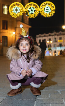 Little girl celebrating christmas under festive street lights