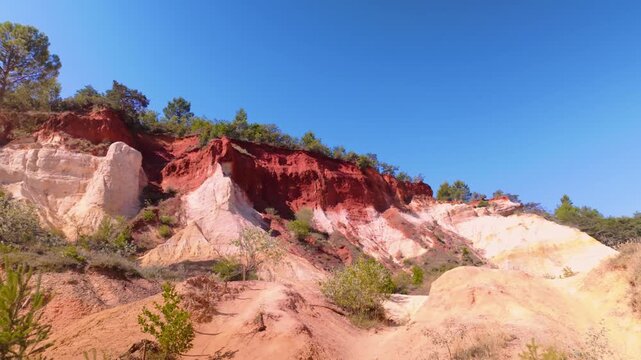 Colorful layered rock cliffs in the Colorado Provencal, a spectacular semi-natural landscape of ancient ochre quarries located next to the village of Rustrel , France. Pan right motion.