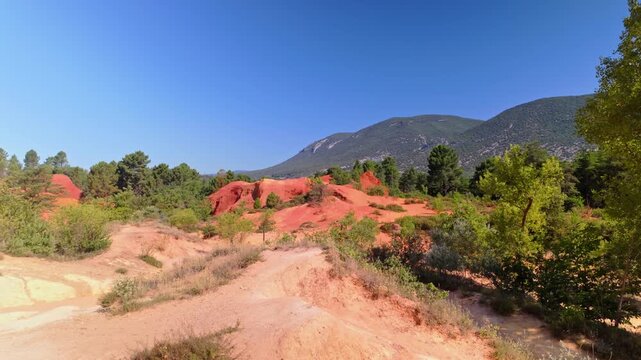 Colorful layered rock cliffs in the Colorado Provencal, a spectacular semi-natural landscape of ancient ochre quarries located next to the village of Rustrel , France. Pan right motion.