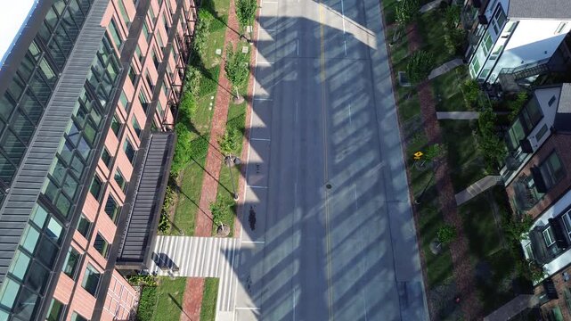 Overhead view highlights linear progression along thoroughfare dividing office facade from townhomes in Coppell, TX. Geometric shadows define spatial distribution between workplaces and homes
