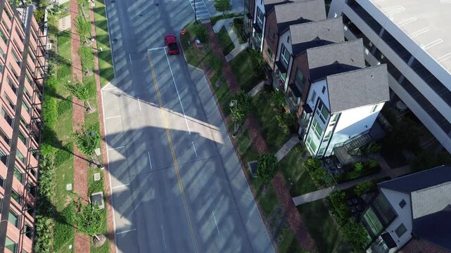 Red vehicle traverses artery connecting professional workspace and residential zones in Cypress Waters, Coppell, TX. Uniform building placement showcases master planned layout prioritizing density
