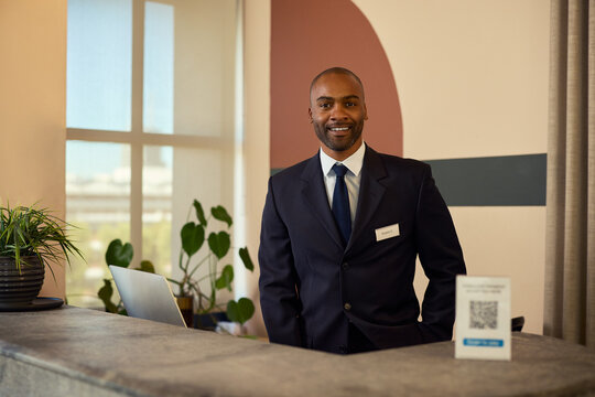 Confident black receptionist at front desk smiling