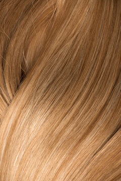 Blond hair background, lock of long straight hair, healthy and beauty dyed hair backdrop design, salon, treatment, cure, dying concept. Close up, top view, vertical photo
