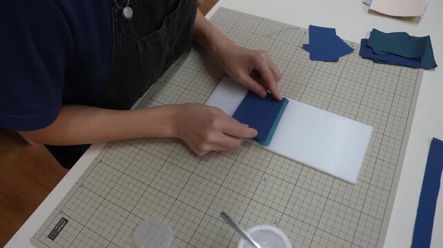 Craftsperson aligns cut leather square against white paper template