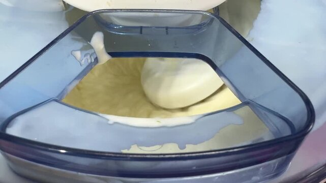 Kitchen mixer kneads soft dough in a large metal bowl until elastic and smooth, flour dust rises, yeast aroma fills the kitchen, rustic homemade bread, a candid authentic life scene.