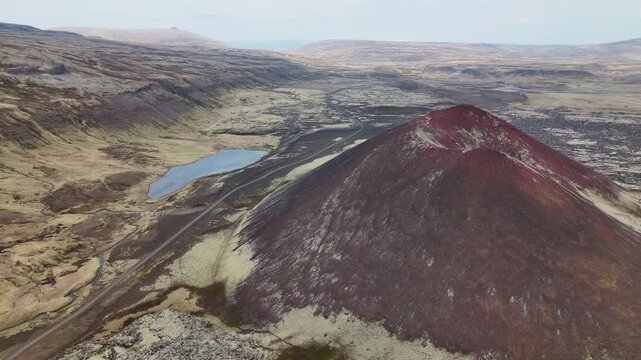 Isolated volcanic cone emerging from rugged lava landscape, western Snaefellsnes, Iceland