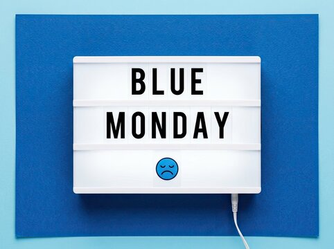 illuminated sign with 'BLUE MONDAY' text and sad face emoji, against a vibrant blue background, conveying the feeling of melancholy and the start of the work week