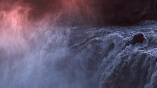 Massive water spray erupting from Aldeyjarfoss cascade with pink sunset glow, North Iceland