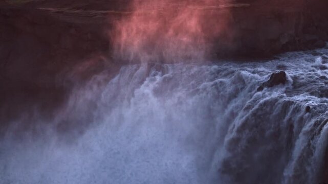 Thundering cascade of Aldeyjarfoss illuminated by soft pink arctic light, North Iceland