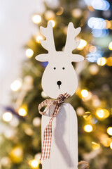 White wooden reindeer decoration with a plaid ribbon bow. © Olga