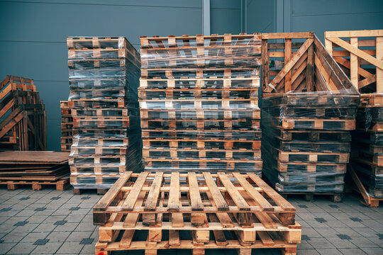 Used euro pallets wrapped in stretch film outside a warehouse. Industrial logistics, supply chain management and freight storage concept.