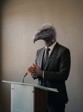 Speaker, politician or salesperson represented as a vulture behind lectern, rubbing his hands. AI generated.