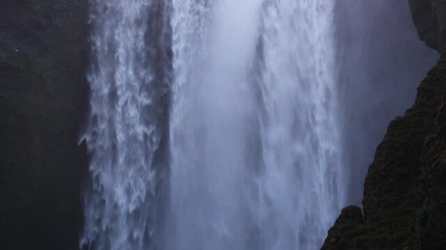 Tight frame on Skogafoss water wall between basalt walls atmospheric shot for nature docs, Iceland