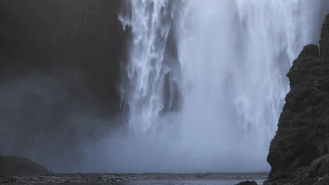 Mist rises at Skogafoss base as evening light fades establishing shot for nature docs, the Southern Region