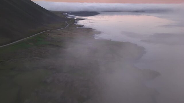 Sweeping aerial over the coastal Ring Road and black sand flats as fog disperses at dawn, Vestrahorn, Iceland