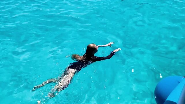 A teenage girl swims in a lagoon with crystal-clear turquoise waters in the Mediterranean Sea. Summer vacations, active leisure, adventure travel, and seaside recreation.